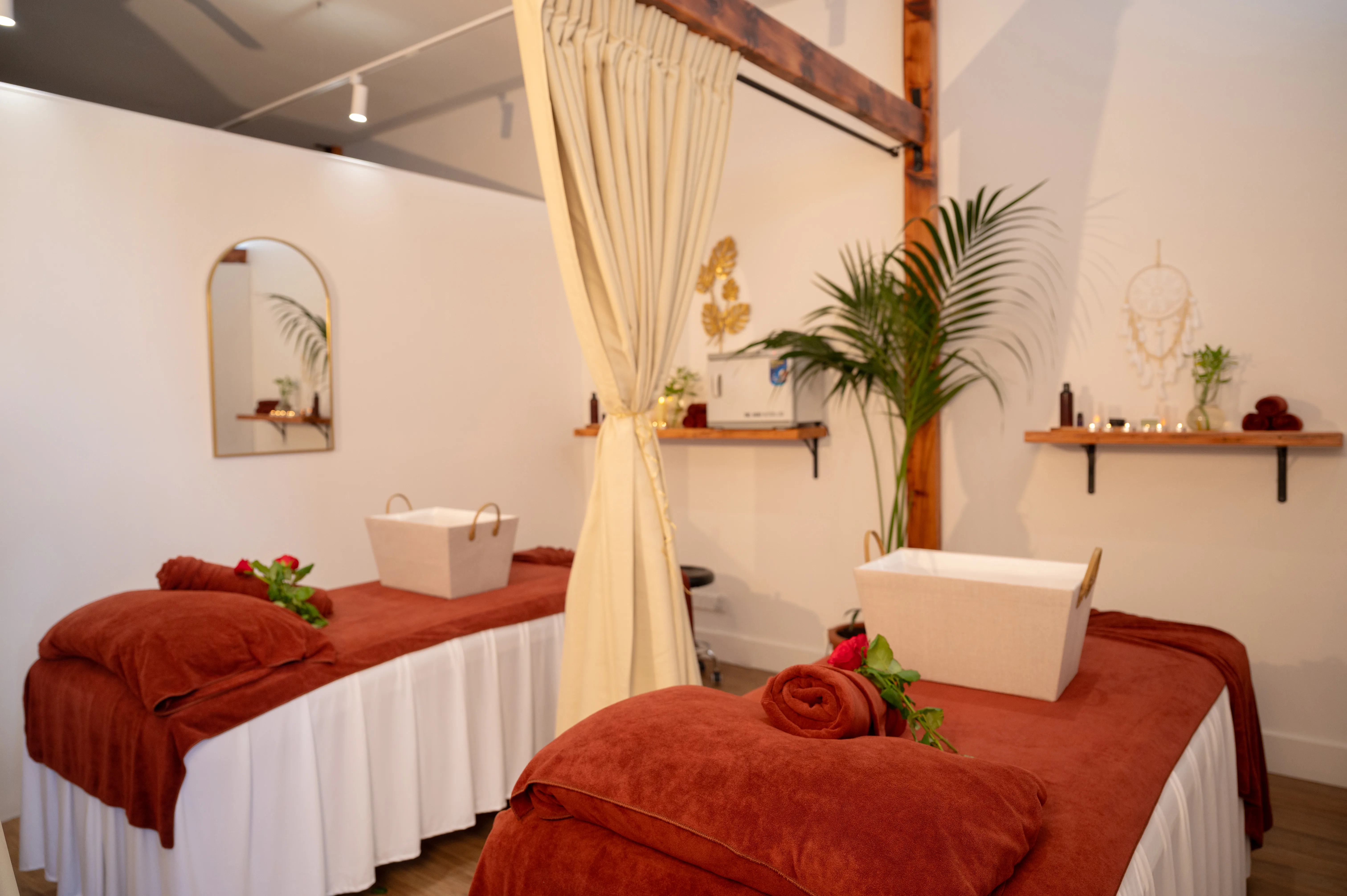 Duo treatment room — terracotta beds, cream canopy, potted palm and gold accents